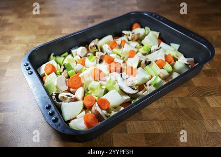 Mirepoix di cottura, miscuglio di verdure crude a dadini come carote, cipolle, sedano, porri e funghi in un piatto da forno, parte della cucina francese, fl Foto Stock