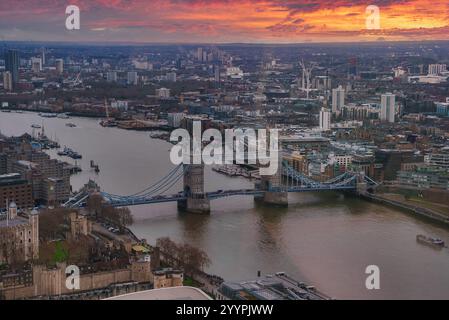 Vista del Tower Bridge che attraversa il Tamigi a Londra al tramonto. Il cielo è dipinto in tonalità arancio e rosso, riflettendo sul fiume sottostante. Foto Stock