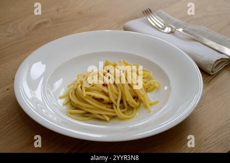 Spaghetti Colatura di Alici con aglio e peperoncini su piatto bianco Foto Stock