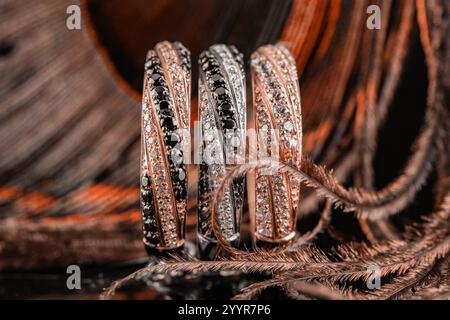 tono di pantone. un set di tre anelli. gioielli sullo sfondo delle piume di pavone. tre anelli con pietre. fedi nuziali in oro e argento. Foto Stock