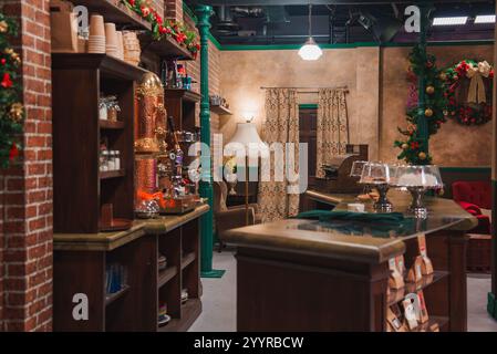 Replica dettagliata del caffè Central Perk presenta una macchina da caffè d'epoca, comodi posti a sedere e decorazioni festive, adagiati in una calda atmosfera con pareti in mattoni Foto Stock