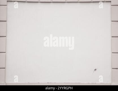 pantone 2025. Muro bianco di un edificio con mattoni lungo il perimetro. Parete grigio chiaro che sembra uno schermo per guardare film con il proiettore. Foto Stock