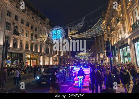 Una vivace scena sulla Regent Street di Londra durante il Natale, caratterizzata da globi illuminati, figure angeliche e architettura storica in mezzo a una vivace atmosfera Foto Stock