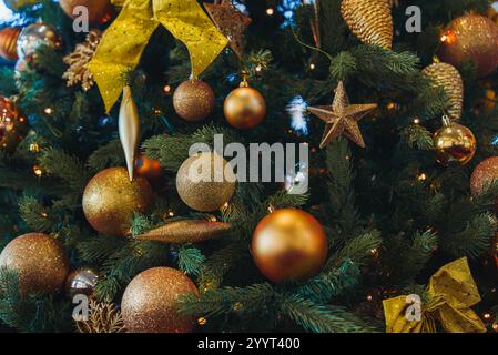 Un lussureggiante albero di Natale verde è adornato con baule dorate, una stella e un grande arco, illuminato da luci calde, che catturano il tifo delle festività natalizie a lo Foto Stock