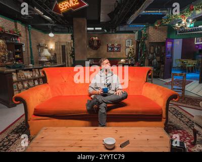 Persona seduta sull'iconico divano arancione al Central Perk Replica di Londra Foto Stock