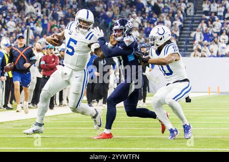 Indianapolis, Indiana, Stati Uniti. 22 dicembre 2024. Il quarterback degli Indianapolis Colts Anthony Richardson (5) corre con la palla e le braccia rigide della safety dei Tennessee Titans Amani Hooker (37) durante la gara NFL al Lucas Oil Stadium di Indianapolis, Indiana. John Mersits/CSM/Alamy Live News Foto Stock