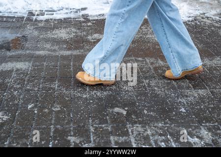 Prodotti chimici antigelo. Donna che cammina per strada trattata con sale tecnico o prodotti chimici antighiaccio Foto Stock