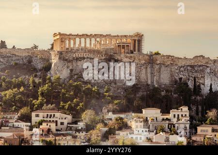 Atene, Attica - GR - 27 ottobre 2024 il Partenone in cima all'Acropoli di Atene, Grecia, con vegetazione lussureggiante e affascinanti case del quartiere Plaka Foto Stock