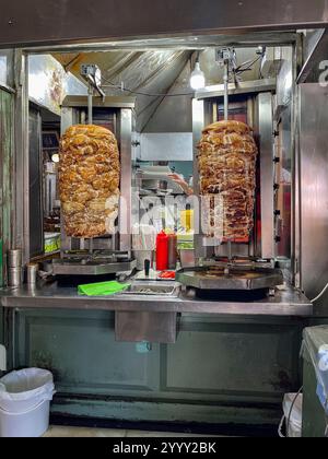 Atene, Attica - GR - 27 ottobre 2024 Un accogliente caffè greco ad Atene con giroscopi freschi su girarrosti verticali, circondati da ingredienti vivaci e un Foto Stock