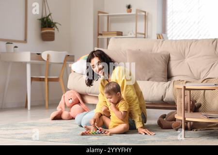 Bella, giovane, felice madre e piccolo bambino che gioca con lo xilofono a casa Foto Stock