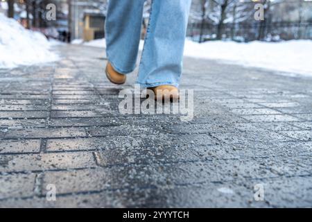 Prodotti chimici antigelo. Donna che cammina per strada trattata con sale tecnico o prodotti chimici antighiaccio Foto Stock