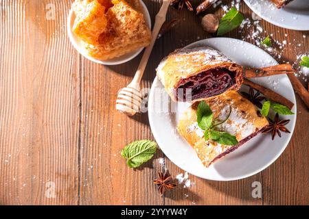 Strudel di ciliegia autunnale profumato fatto in casa con uvetta, noci, miele, spezie alla cannella, su piatto, spazio copia sul tavolo della cucina Foto Stock