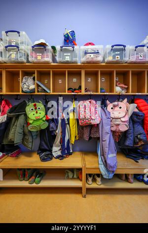 Germania - immagine simbolica KITA. Cappotti, giacche e zaini di unicorno di bambini appesi a un guardaroba in un asilo. Foto Stock