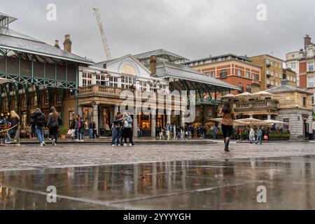 Turisti che visitano il mercato dei giardini di covent a londra in una giornata di pioggia Foto Stock