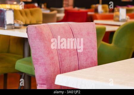 Sedie colorate disposte in un luminoso interno del ristorante Foto Stock