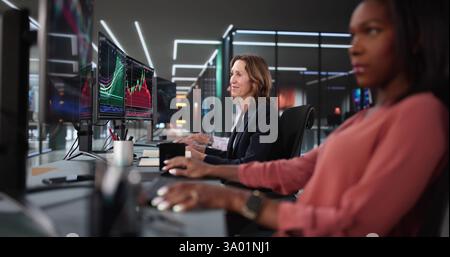 Team di intermediari azionari impegnati in ufficio che analizza grafici e dati. Analista americano che usa il computer per commerciare sul mercato. Foto Stock