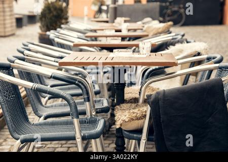 Un affascinante caffè all'aperto con tavoli vuoti e sedie intrecciate in una strada acciottolata in una città europea. Un ambiente perfetto per i viaggi, l'ospitalità e. Foto Stock