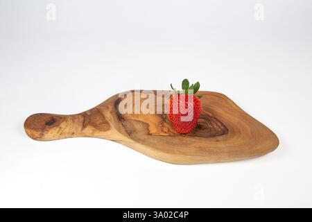 Fragola su tagliere in legno di oliva isolata su sfondo bianco. Foto Stock