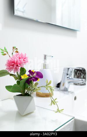 Arredi minimalisti del bagno con fiori artificiali in vaso bianco. Foto Stock