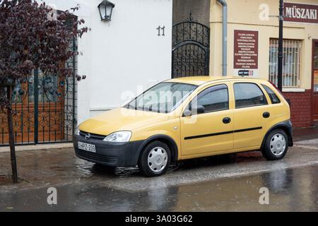 TOKAJ, UNGHERIA - 27 OTTOBRE 2023: Piccola berlina gialla Opel corsa C parcheggiata in strada sotto la pioggia Foto Stock