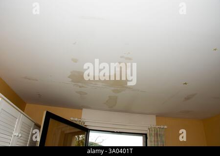 Macchie d'acqua sul soffitto della stanza che rivelano una potenziale perdita del tetto durante il giorno Foto Stock