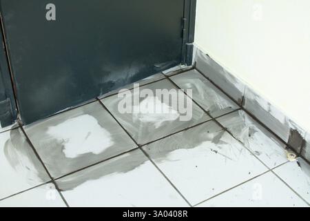 Fissaggio di piastrelle danneggiate in uno spazio commerciale prima della riapertura Foto Stock