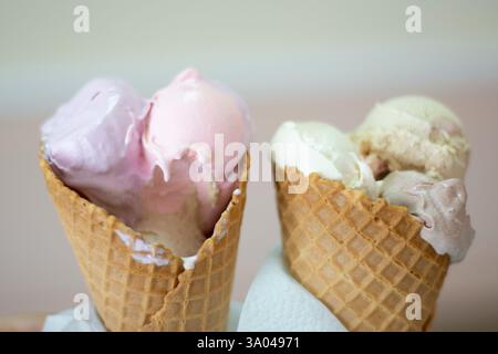 Un paio di gelati da latte che si fondono in coni per biscotti Foto Stock