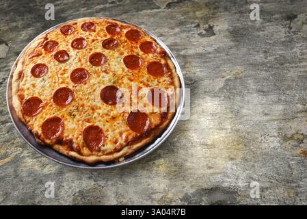 Una pizza al peperoni fatta in casa appena sfornata su un tavolo in ardesia, con spazio per le copie. Foto Stock