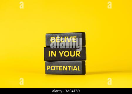 Credete nel vostro potenziale. Slogan motivazionale, fiducia aziendale, supporto aziendale. Parole concettuali. Sfondo giallo e iscrizione su legno nero b Foto Stock