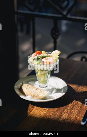 Aperitivo con cocktail di gamberi con verdure servito con pane marrone in un bicchiere su un tavolo di legno nel ristorante Foto Stock
