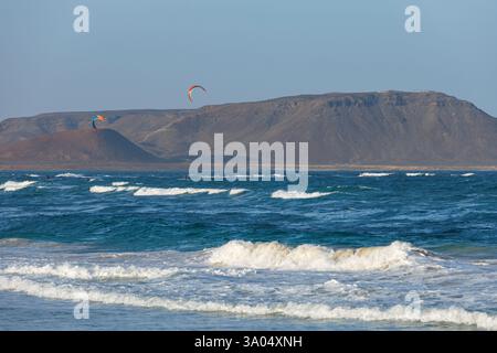 I kiteboarder vengono tirati attraverso l'acqua da un aquilone elettrico a Costa da Fragata, a sud-est dell'isola di Sal Foto Stock