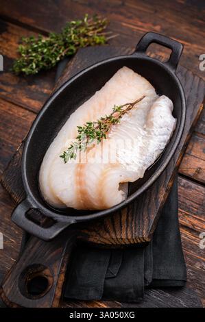 Filetto di merluzzo crudo incontaminato, in attesa di essere marinato e cucinato alla perfezione per una deliziosa esperienza culinaria. sfondo in legno. vista dall'alto. Foto Stock