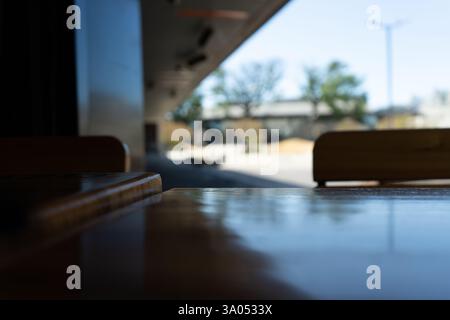 La superficie del tavolo in legno lucido risplende alla luce del sole in un caffè all'aperto, creando un'atmosfera tranquilla e invitante Foto Stock