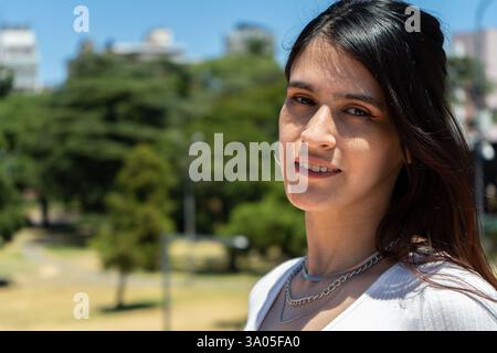 Ritratto di una giovane donna latina alla moda che si gode una giornata di sole in un parco cittadino Foto Stock