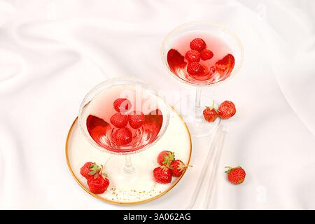 Cocktail alcolico festivo, martini rossi in bicchieri su sfondo luminoso con fragole, concetto bar estivo, bevande alcoliche a una festa, restaura Foto Stock