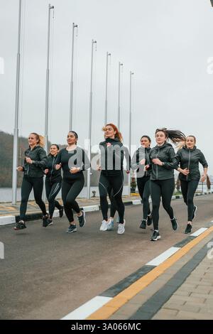 Correndo insieme. Un gruppo di donne sportive si trova all'aperto vicino all'edificio nero. Foto Stock