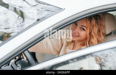 Con la porta aperta. La giovane donna è seduta nell'automobile. Foto Stock