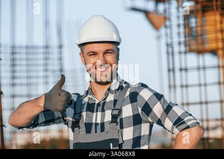 Il lavoratore felice è in piedi sul cantiere durante il giorno. Foto Stock