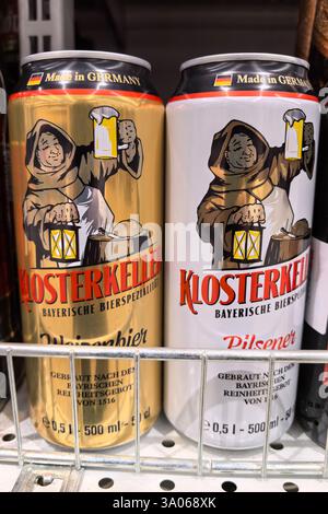 Bobruisk, Bielorussia - 22 febbraio 2025: Due distinte lattine di birra tedesche si trovano affiancate su uno scaffale, con intricate illustrazioni di un monaco. Foto Stock