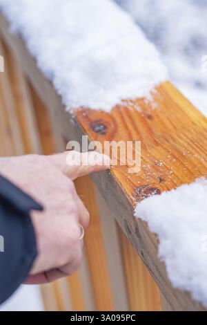 Persona che indica una recinzione in legno ricoperta di neve in un ambiente invernale, nuova passerella in legno nel giardino della città di Calw, Calw, Foresta Nera, Germania, Europa Foto Stock