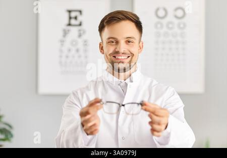 Oculista maschio sorridente o infermiere che tiene gli occhiali in clinica Foto Stock