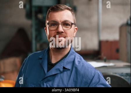 Ritratto del lavoratore di fabbrica che è in uniforme blu in interni. Foto Stock