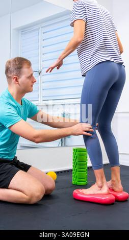 Donna con dolore alla caviglia in terapia fisica. Fisioterapista che esercita con paziente femminile. Foto Stock