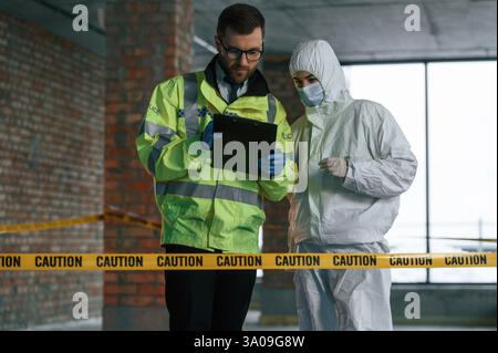 Con blocco note. Due detective stanno raccogliendo prove su una scena del crimine. Gli specialisti forensi stanno facendo esperienza. Foto Stock