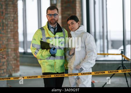 In piedi e in posa. Due detective stanno raccogliendo prove su una scena del crimine. Gli specialisti forensi stanno facendo esperienza. Foto Stock