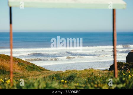 Onde oceaniche viste attraverso una cornice rustica in legno a Praia da Almag Foto Stock