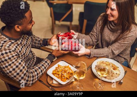 Due amici cenano al ristorante. Si stanno scambiando regali. Foto Stock