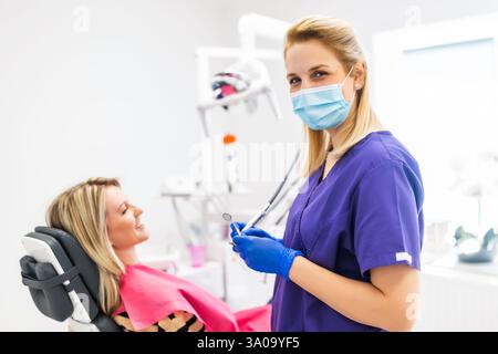 Dentista che ripara i denti del paziente. Giovane donna che ha i denti esaminati e riparati. Foto Stock