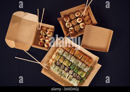 Vista dall'alto dei sushi roll presenti nelle scatole ecologiche di carta sul tavolo. Foto Stock
