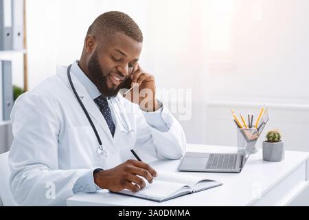Giovane medico africano che parla con il paziente al telefono Foto Stock